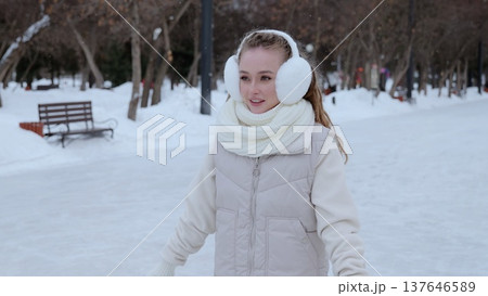 Cheerful female gliding across icy rink, bundled in warm winter accessories, embracing seasonal recreation with joyful expression 137646589