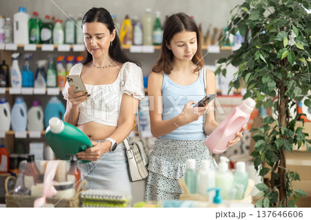 Woman with teen daughter buyer scans qr code on liquid laundry powder label Woman with teen daughter buyer scans qr code on liquid laundry powder label 137646606