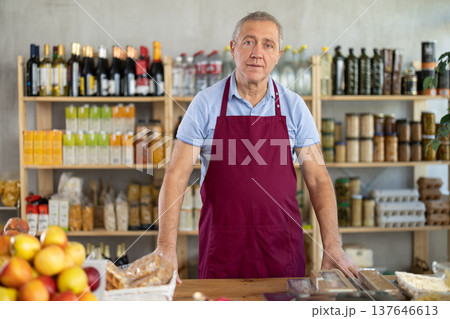 Elderly man seller at counter in grocery store 137646613