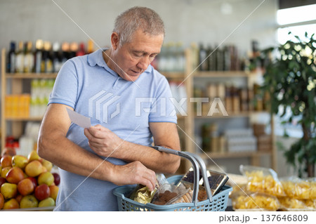 Elderly man buying groceries from shopping list in store 137646809