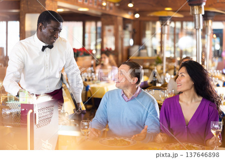 Man and woman talking with waiter in restaurant 137646898