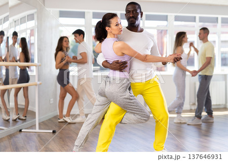 Middle-aged man and woman practicing tango dance in pair in training hall Middle-aged man and woman practicing tango dance in pair in training hall 137646931