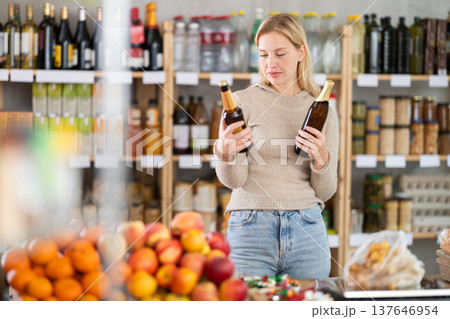 Shopping in produce supermarket - female buyer makes choice bottle of beer 137646954