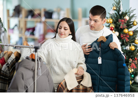Young couple chooses down jackets in store Young couple chooses down jackets in store 137646958