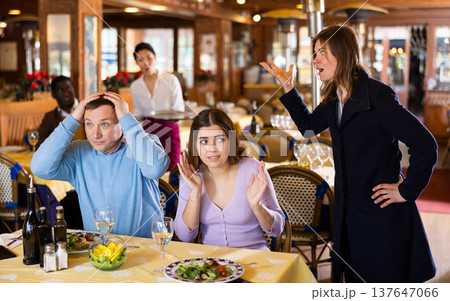 Wife scolding husband spending time with another woman in restaurant Wife scolding husband spending time with another woman in restaurant 137647066