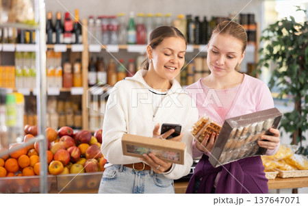 Two customers scan the barcode of candy packages Two customers scan the barcode of candy packages 137647071