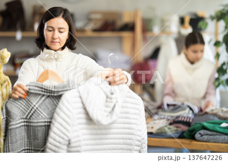 Woman looks at products in store and selects coat or jacket. Family shopping 137647226