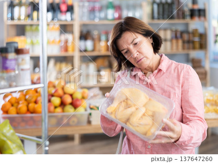 Mature woman choosing chicken in grocery store Mature woman choosing chicken in grocery store 137647260