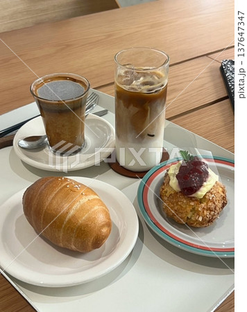 A delightful assortment of desserts displayed in a cozy cafe setting, featuring cakes, pastries, and sweet treats on elegant plates, creating a warm and inviting atmosphere. 137647347