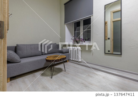 Minimalist Hostel Room with Grey Sofa and Unique Wood Slab Table Minimalist Hostel Room with Grey Sofa and Unique Wood Slab Table 137647411