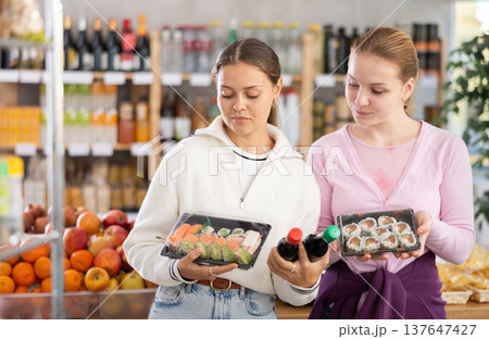 Young women choose sushi rolls and soy sauce 137647427