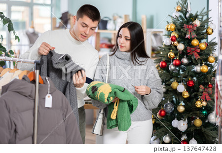 Young couple choosing sweater in store Young couple choosing sweater in store 137647428