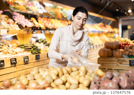 In vegetable store, young woman customer buy ripe potato 137647576