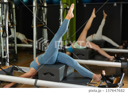 Woman in sports top and leggings doing exercises on reformer 137647682