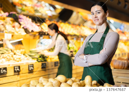 Adult woman seller offers potatoes in vegetable shop Adult woman seller offers potatoes in vegetable shop 137647687