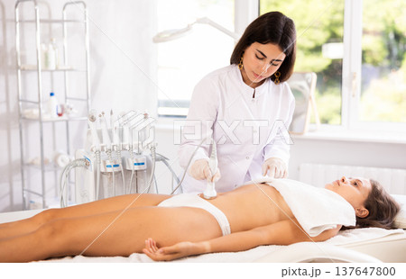 Female doctor making belly beauty massage with vibration attachement Female doctor making belly beauty massage with vibration attachement 137647800