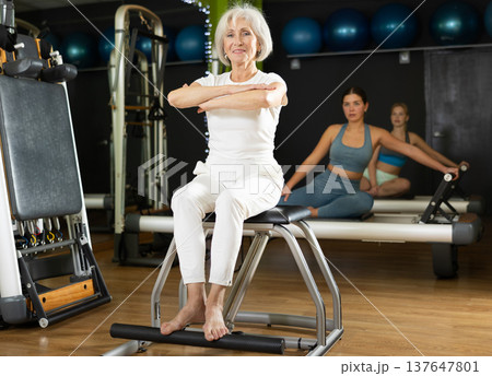 Senior woman perform pilates exercises using lifes beach pilates chair Senior woman perform pilates exercises using lifes beach pilates chair 137647801