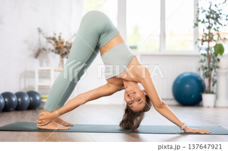 Woman exercising warrior one pose during yoga training in gym Woman exercising warrior one pose during yoga training in gym 137647921