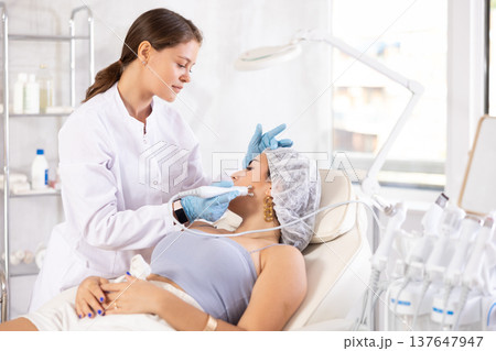 European doctor making beauty massage to brunette girl European doctor making beauty massage to brunette girl 137647947