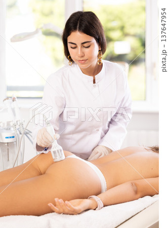 Cosmetologist performing hardware procedure on female buttocks using cooling attachment Cosmetologist performing hardware procedure on female buttocks using cooling attachment 137647954
