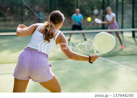 Woman playing padel tennis match during training on court Woman playing padel tennis match during training on court 137648200