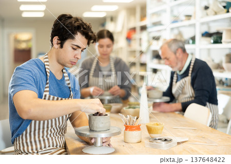 Young man sculpts ceramic piece in workshop Young man sculpts ceramic piece in workshop 137648422