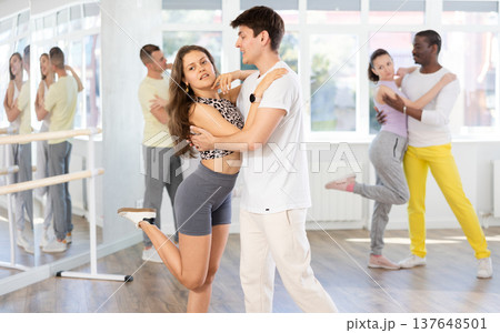 Happy pretty woman enjoying impassioned merengue with male partner in dance room during class. Social dancing concept Happy pretty woman enjoying impassioned merengue with male partner in dance room during class. Social dancing concept 137648501