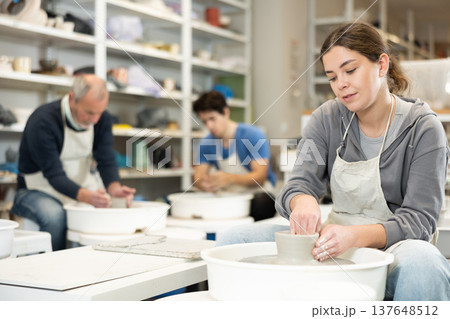 Young woman shaping pottery on wheel in ceramics studio Young woman shaping pottery on wheel in ceramics studio 137648512