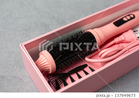 Ideal pink electric multi-styler for any hairstyle. Cylindrical brush with comb and clips on neutral background. Achieve curls, volume, or sleek straight looks effortlessly Ideal pink electric multi-styler for any hairstyle. Cylindrical brush with comb and clips on neutral background. Achieve curls, volume, or sleek straight looks effortlessly 137649673