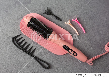 Sustainable pink electric multi styler for eco conscious beauty lovers. Reusable hair tool replaces multiple devices, reducing waste. Complete kit with comb and clips on natural background Sustainable pink electric multi styler for eco conscious beauty lovers. Reusable hair tool replaces multiple devices, reducing waste. Complete kit with comb and clips on natural background 137649688