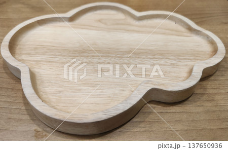 A carved wooden serving plate with decorative shape placed on a table, representing rustic restaurant tableware and antique-style food presentation A carved wooden serving plate with decorative shape placed on a table, representing rustic restaurant tableware and antique-style food presentation 137650936