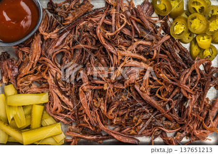 Slow cooked pulled beef with jalapeno slices and pickles, barbecue meat tray on light stone background, overhead.. 137651213