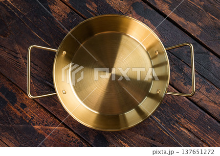 Empty shiny metal saute pan on dark wooden background, professional kitchen utensil for cooking and food preparation Empty shiny metal saute pan on dark wooden background, professional kitchen utensil for cooking and food preparation 137651272