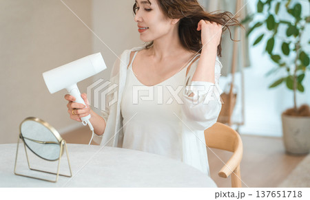 ヘアドライヤーでヘアブロー・髪の毛を乾かす女性（ヘアケア） 137651718