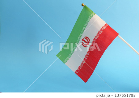 Iran flag against a blue sky background symbolizing political tension and crisis. Close-up view of the Iranian flag representing current geopolitical conflicts, social unrest, and international Iran flag against a blue sky background symbolizing political tension and crisis. Close-up view of the Iranian flag representing current geopolitical conflicts, social unrest, and international 137651788