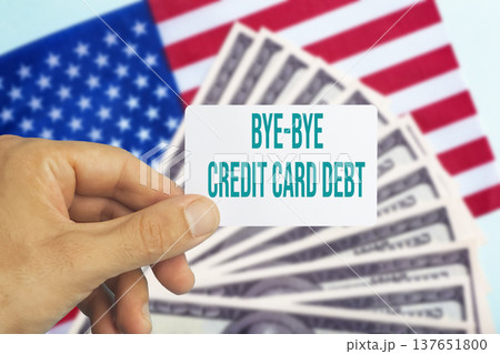 Human hand holding a plastic credit card with text bye bye credit card debt against a background of US dollar bills. Conceptual photography symbolizing financial freedom, paying off personal loans Human hand holding a plastic credit card with text bye bye credit card debt against a background of US dollar bills. Conceptual photography symbolizing financial freedom, paying off personal loans 137651800