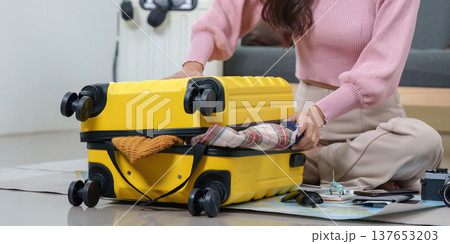 Travel Preparation. Woman packing yellow suitcase with clothes and accessories for vacation. 137653203