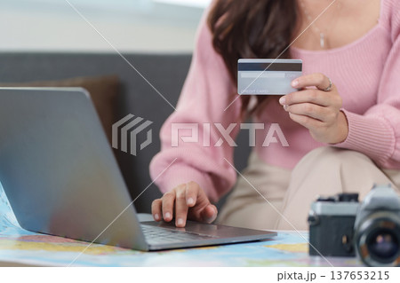 Online Booking. Woman using laptop for travel arrangements with credit card. 137653215