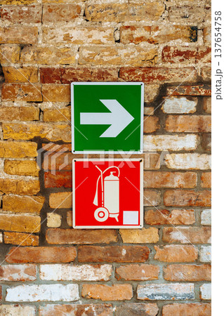 Signs guide people towards the exit and fire equipment on a brick wall Signs guide people towards the exit and fire equipment on a brick wall 137654758