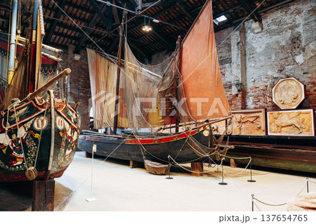 Old boats and artifacts displayed in an indoor maritime museum in a historic city 137654765