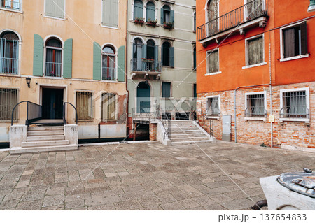 Square in Venice with buildings and stairs near a canal in midday light 137654833
