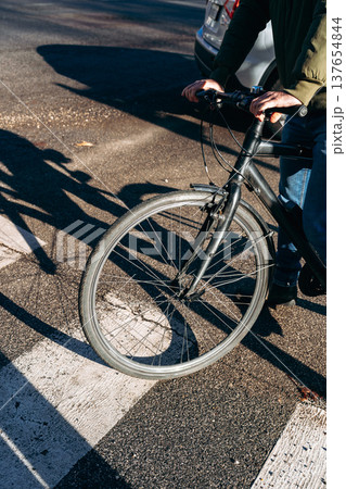 Person rides a bicycle on the street during daylight hours in an urban area 137654844