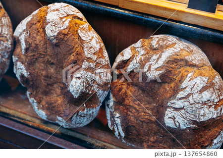 Freshly baked round loaves of bread presented on a wooden shelf in a bakery Freshly baked round loaves of bread presented on a wooden shelf in a bakery 137654860