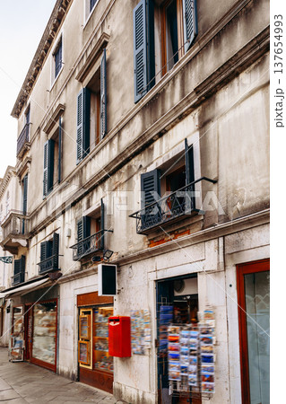 Building with balconies and a post box in a street with shops in a city 137654993