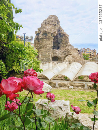 Old Nessebar stone church ruins with tower and arches above garden roses in coastal Bulgaria under cloudy sky. Ancient City of Nessebar, Bulgaria inscribed as UNESCO World Heritage Site 137655287