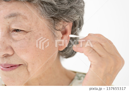 綿棒で耳掃除をするシニア女性 綿棒で耳掃除をするシニア女性 137655317