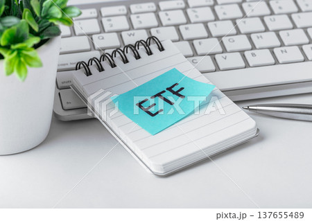 ETF sticky note on notebook with computer keyboard and pen on work table, etf investment concept, closeup ETF sticky note on notebook with computer keyboard and pen on work table, etf investment concept, closeup 137655489