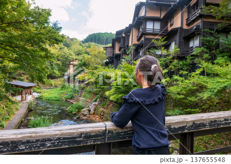 Japanese girl on bridge look at Kurokawa onsen town by river, Kumamoto Japanese girl on bridge look at Kurokawa onsen town by river, Kumamoto 137655548