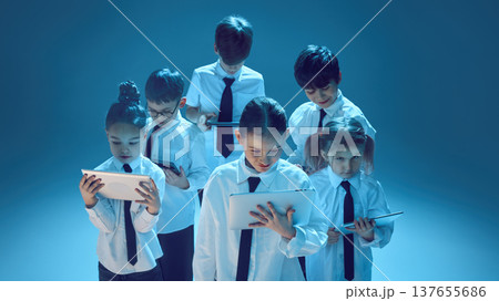 Children focused on tablets in neon studio for digital future concept 137655686