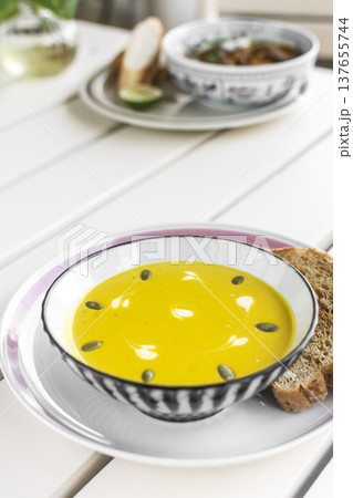 yellow organic pumpkin soup bowl with sourdough toast on restaurant white table outddor yellow organic pumpkin soup bowl with sourdough toast on restaurant white table outddor 137655744